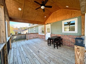 A wooden deck with a ceiling fan, a brick wall, and a window. - Cozy 3-Bedroom Home w/ Covered Deck. Pet-Friendly! (Lawrenceville)