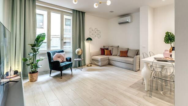 Una sala de estar moderna con un sofá, una mesa de comedor con sillas, un globo terráqueo sobre un atril y una planta grande.