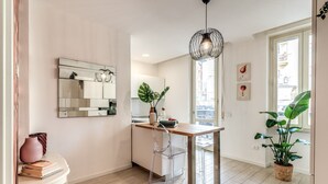Una cocina moderna con una mesa de madera, sillas transparentes, una lámpara colgante y un ventanal grande.