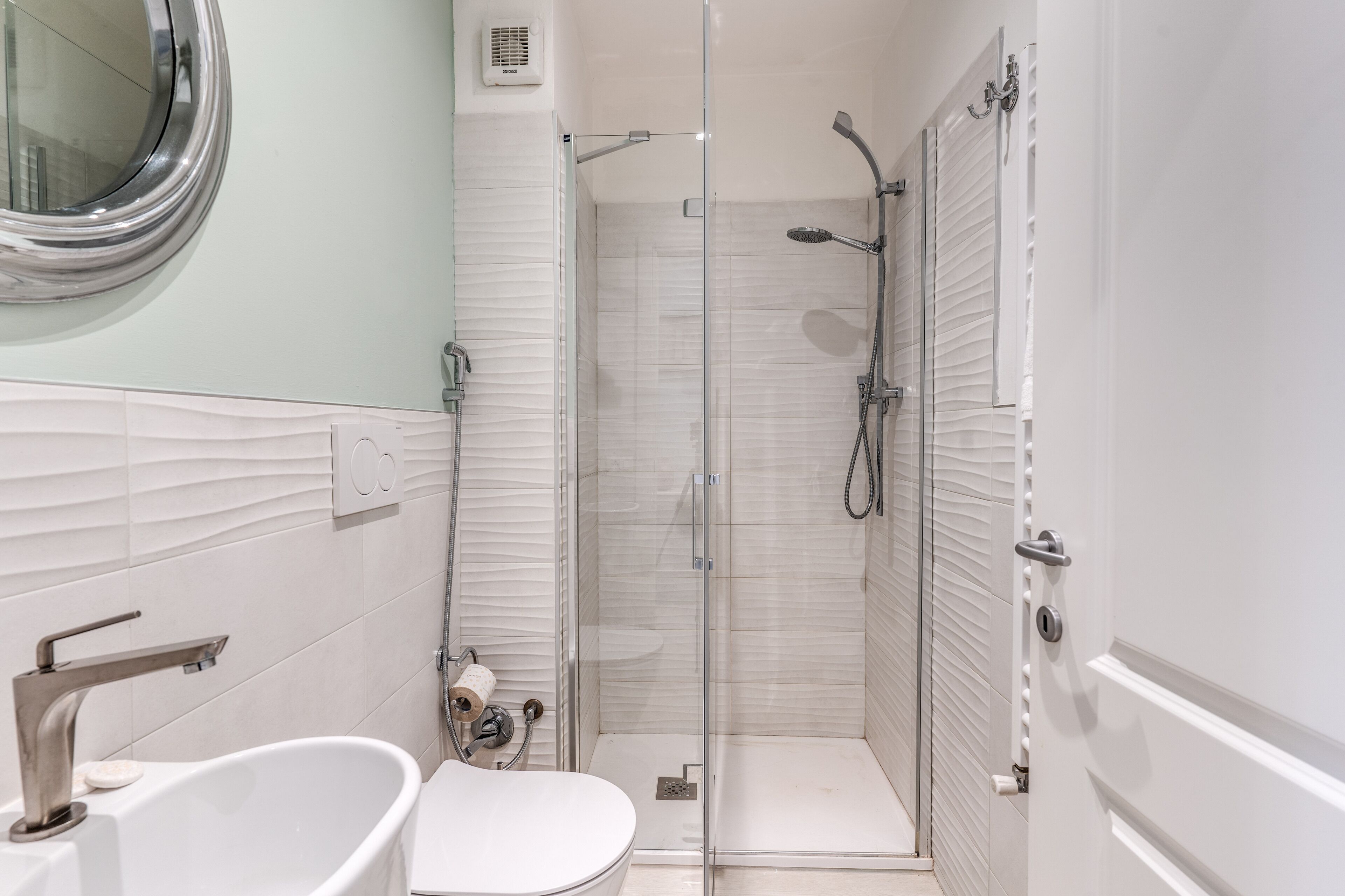 Un bagno moderno con doccia vetro e vasca da bagno indipendente, oltre a un water.
