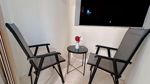 A small balcony with two black mesh chairs and a small round table with a vase of flowers. - Beit Alshabaan Inn (Wadi Musa)