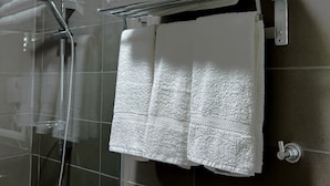 A bathroom with a glass shower enclosure, a metal towel rack with folded towels, and a visible showerhead. - Beit Alshabaan Inn (Wadi Musa)