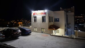 A building with a sign reading "BETT ALSHABAN" at night. - Beit Alshabaan Inn (Wadi Musa)