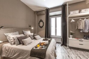 A bedroom with a bed, bedside table, and a window with curtains. - A-Rome Suite  (Rome)