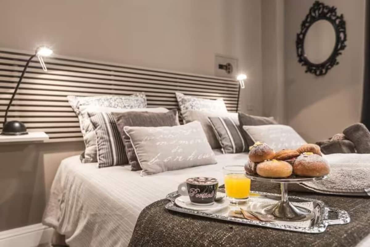 Un letto rifatto con cura, un vassoio con pasticcini, una tazza e un bicchiere di succo d'arancia sul coprimaterasso.