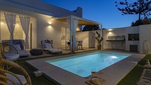A modern outdoor pool area with lounge chairs, a dining set, and a pergola.