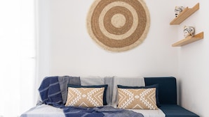 A neatly arranged bed with a blue and white striped bedspread, two patterned pillows, and a blue throw blanket.