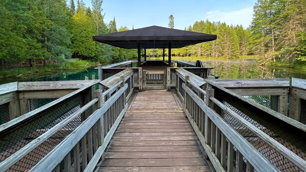 A wooden pier leading to a gazebo over a body of water, surrounded by trees. - Newberry U.P. Cabin (Newberry)