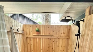 A wooden outdoor shower area with a bench, a towel rack, and a potted plant. - Cabin @ Torch with Lake Access, Kayaks & Outdoor Shower! (Rapid City)