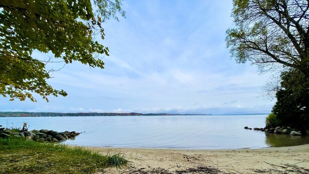 A beach with a calm lake, a sandy shore, and a rocky outcrop. - Cabin @ Torch with Lake Access, Kayaks & Outdoor Shower! (Rapid City)