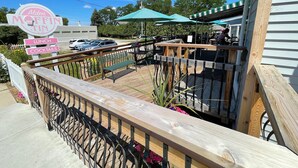 A patio area with a wooden deck, metal railing, and outdoor seating. - Minutes to Torch Lake | Arcades | AC | Fenced Yard (Rapid City)