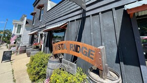 A rustic building with a sign reading "Vista Ridge" and another sign for "Wine Tasting." - Minutes to Torch Lake | Arcades | AC | Fenced Yard (Rapid City)