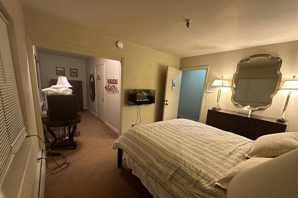 Une chambre d’hôtel avec un lit, un téléviseur fixé au mur, une commode et un miroir.