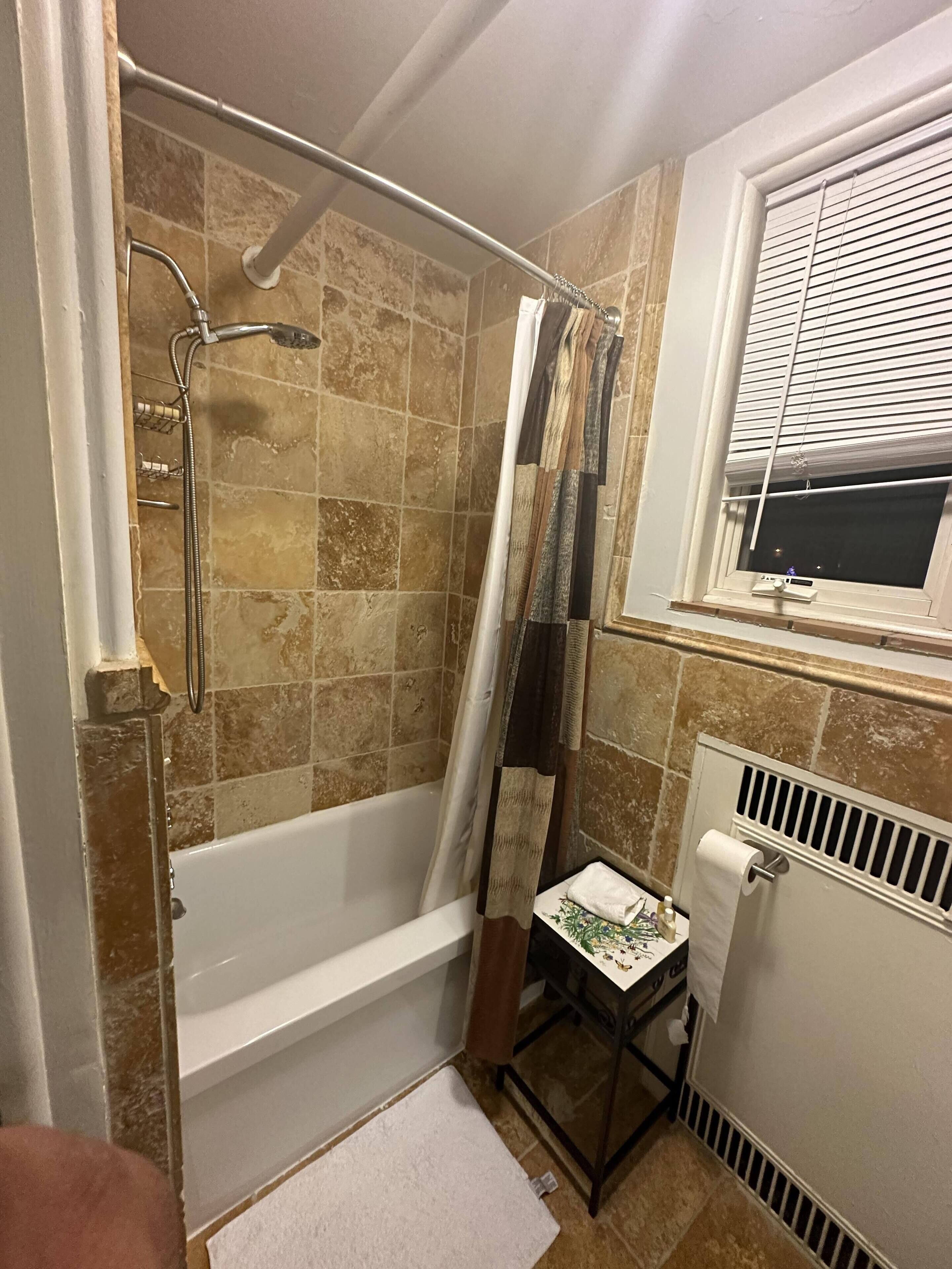 A bathroom with a bathtub, shower, and a window.