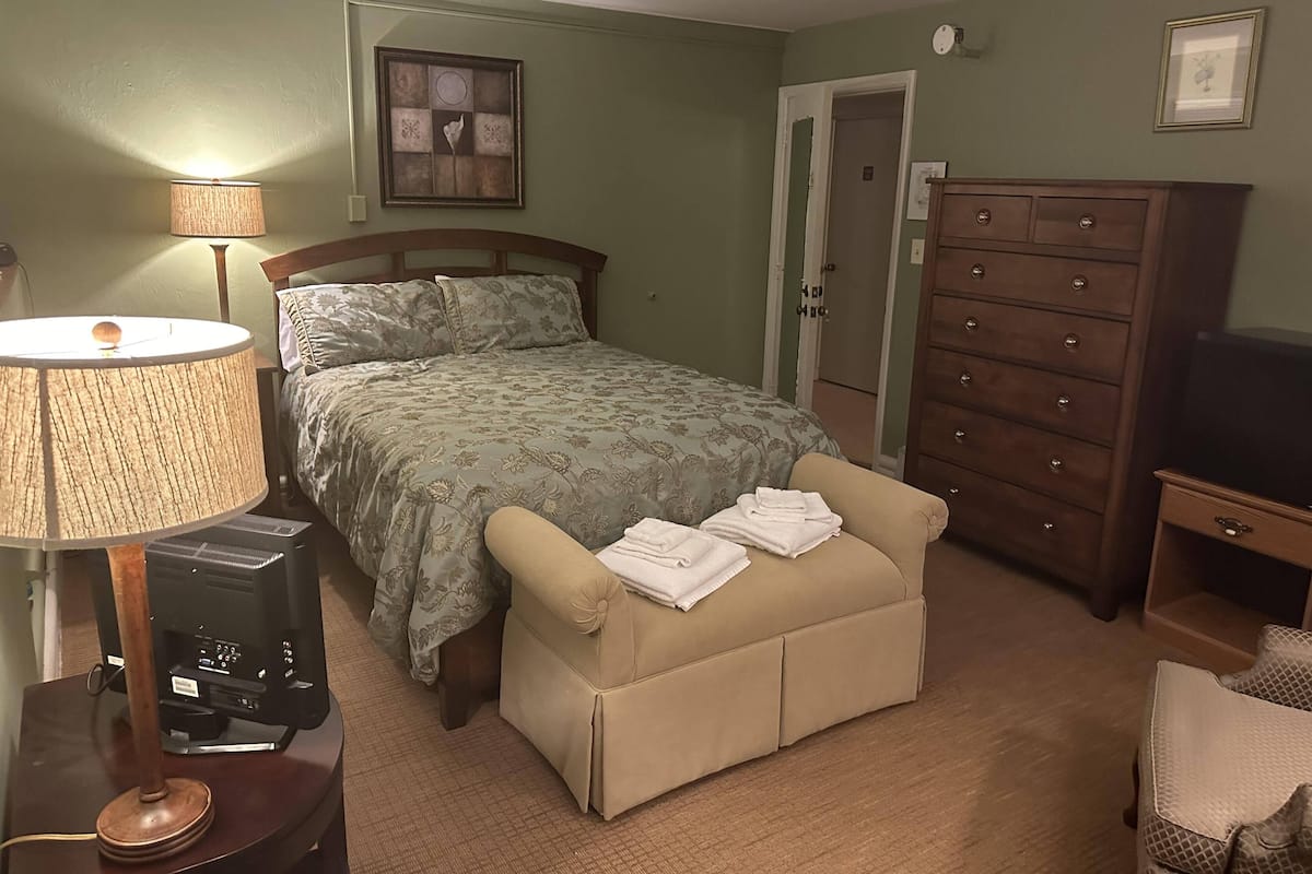 Une chambre à coucher comprenant un lit, une commode, un meuble pour la télévision et une lampe.