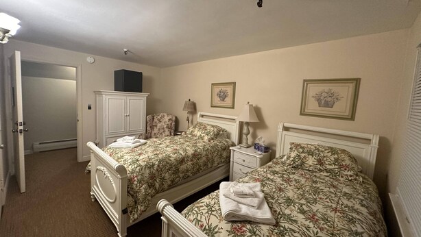 Un dormitorio con dos camas, un armario y una puerta que da a un pasillo.