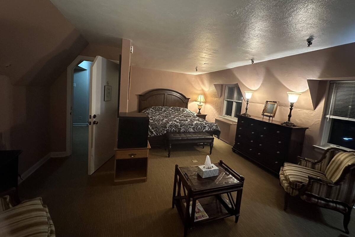 Une chambre à coucher comprenant un lit, des lampes de chevet, une commode, une chaise et une petite table.