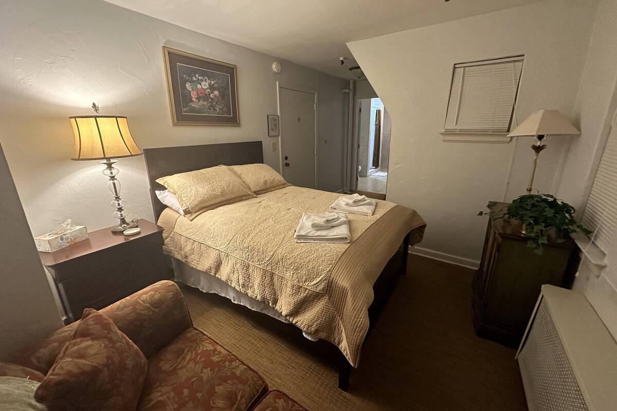 Une chambre à coucher bien rangée, avec un lit, une table de chevet, une lampe et une plante en pot.