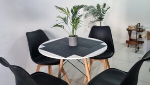 A dining area with a round table, four black chairs, and two potted plants.