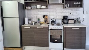 A compact kitchen with a refrigerator, stove, microwave, and wooden cabinets.