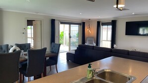 Un salon moderne comprenant un canapé, une table à manger, des chaises et un coin cuisine avec un évier.
