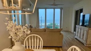 A dining area with a white table, woven placemats, and a vase of white flowers. - Gorgeous Beachfront Condo with 
ocean views (Gulfport)