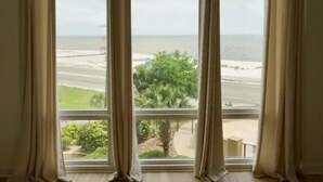 A room with a large window overlooking a beach and a road. - Gorgeous Beachfront Condo with 
ocean views (Gulfport)