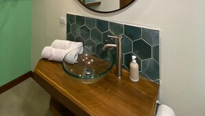 A bathroom with a round mirror, a glass sink, and a wooden vanity. - Oasis by Franklin #9 (La Fortuna)