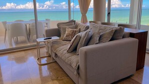 A modern living room with a large window overlooking a beach.
