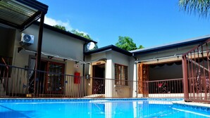 A swimming pool with a house in the background. - Red Apple Guest House (Pretoria)