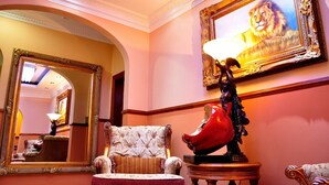 A luxurious room with a large mirror, a plush armchair, and a statue. - Red Apple Guest House (Pretoria)