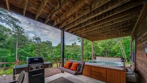 Eine Terrasse im Freien mit Grill, Whirlpool und einer Bank.