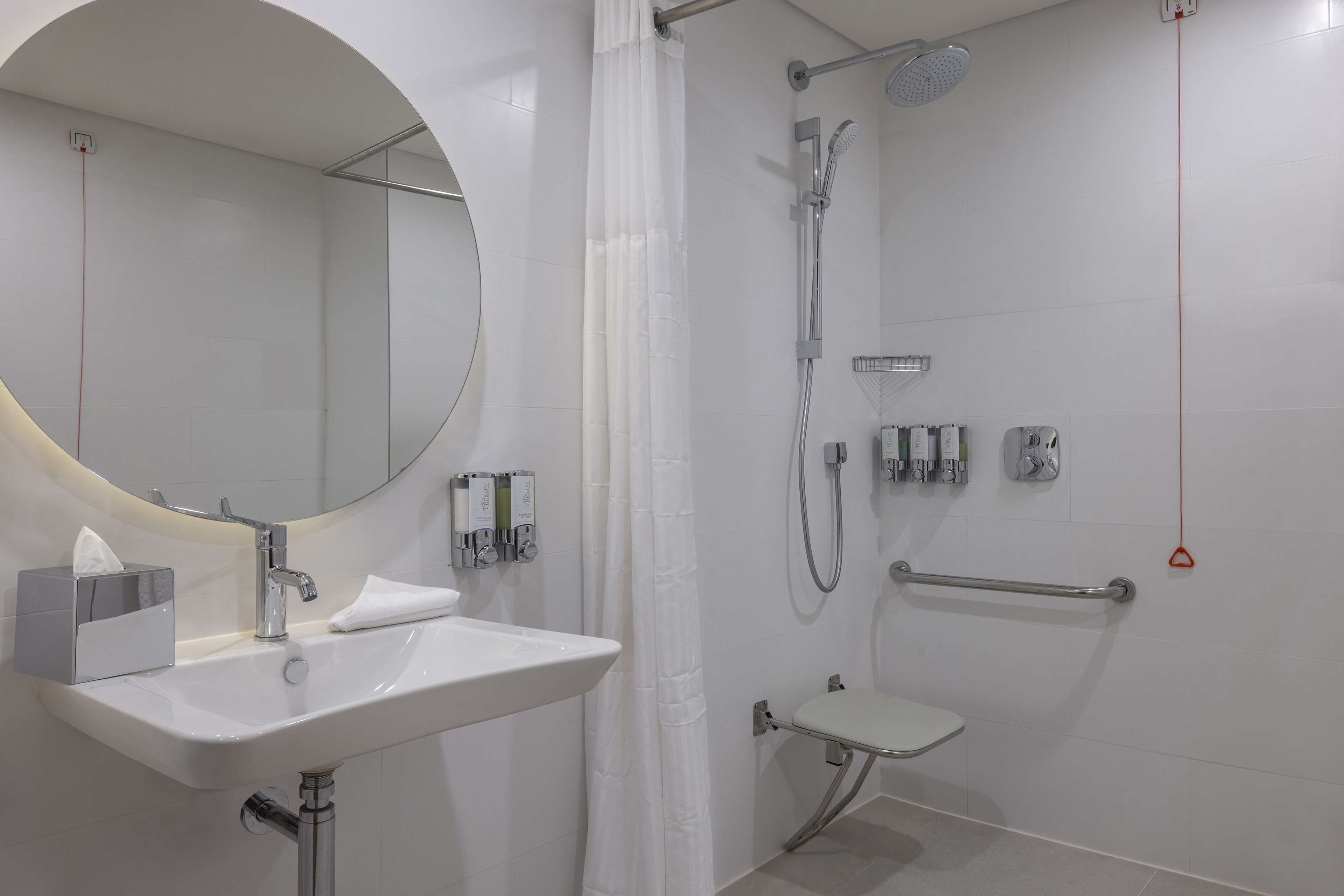 Een moderne badkamer met een witte wastafel, spiegel en douche.