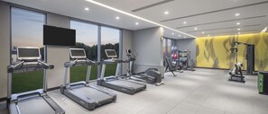 Une salle de sport équipée de tapis de course, de vélos d’exercice et de poids.