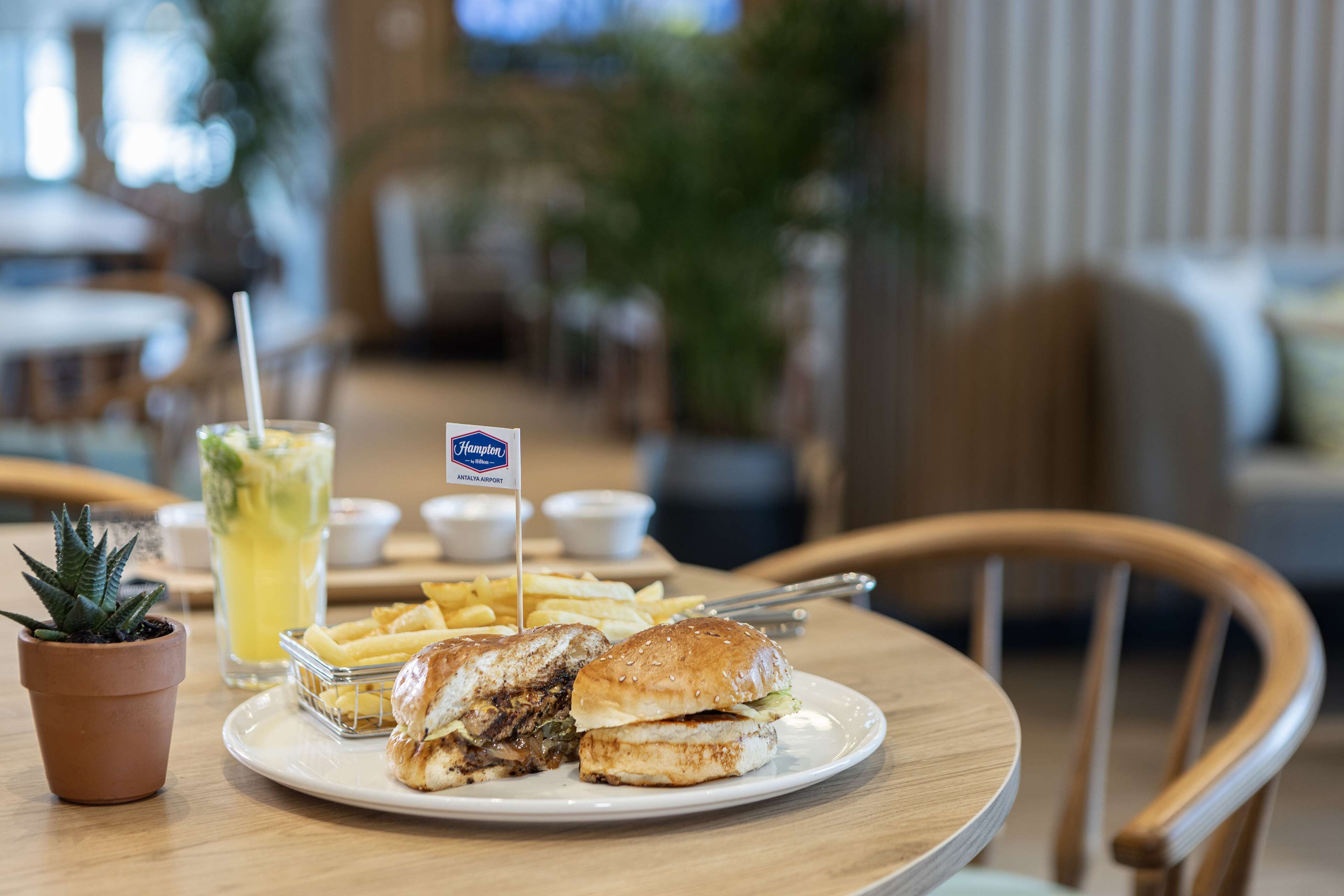 Un restaurante con un plato de comida, que incluye un sándwich, papas fritas y una bebida con pajita.