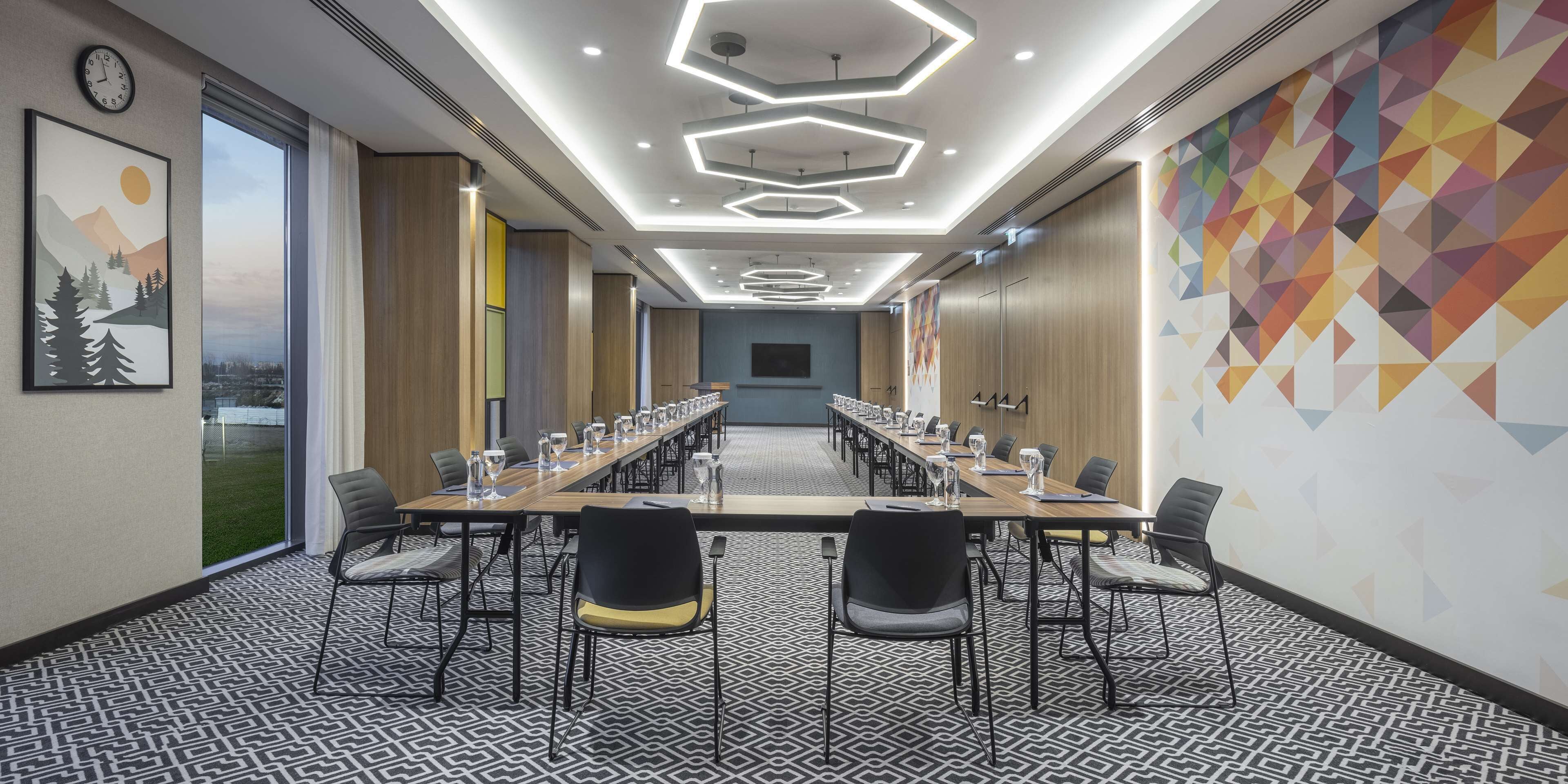 A conference room with a long table, chairs, and a patterned carpet.