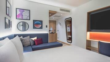 Ein modernes Hotelzimmer mit Bett, einer Sitzecke, einem Fernseher und Kunstwerken an den Wänden.