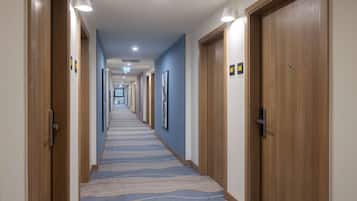 A hotel hallway with wooden doors, blue walls, and a patterned carpet.
