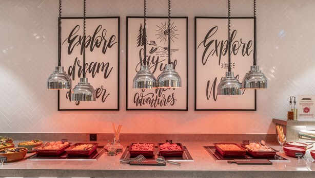 Een buffetopstelling met diverse soorten eten en bestek, omringd door motiverende posters en hangende吊り下げ型ライト.