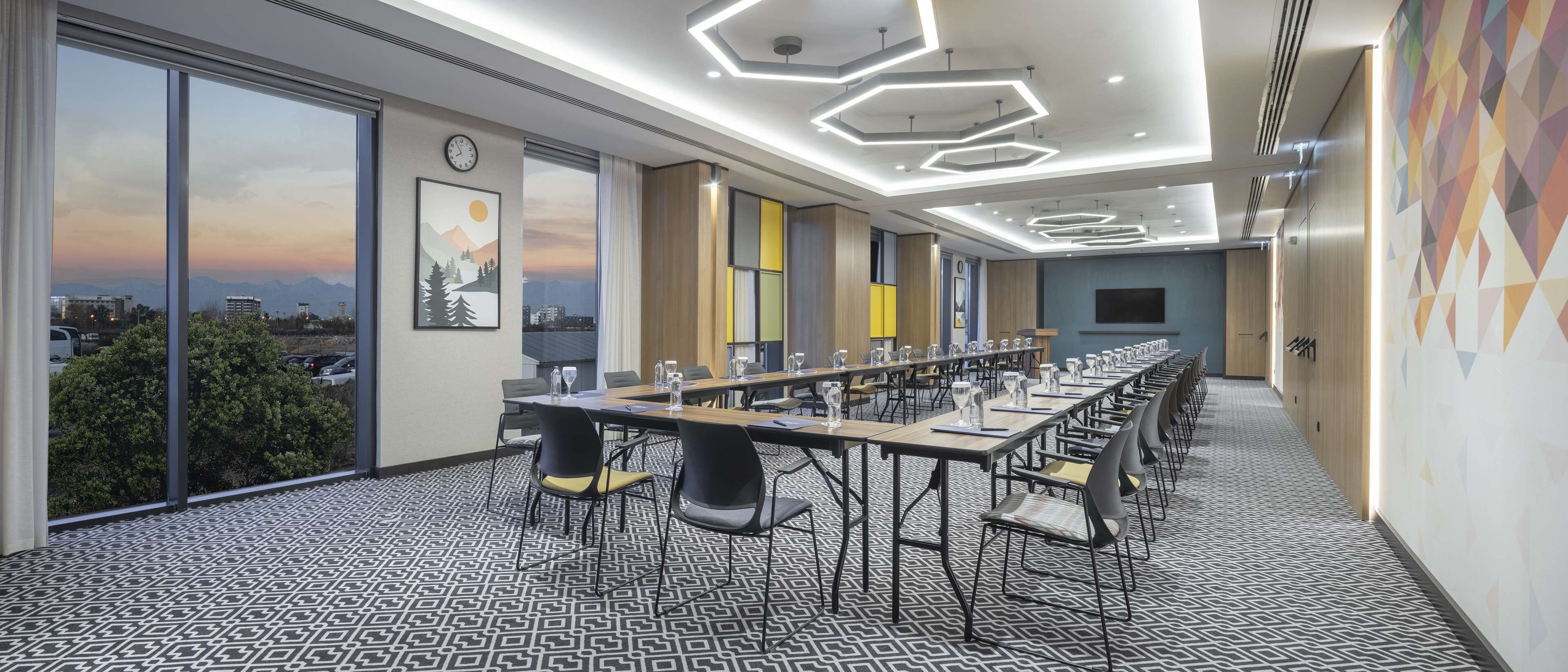 A conference room with a long table, chairs, and a city view through large windows.