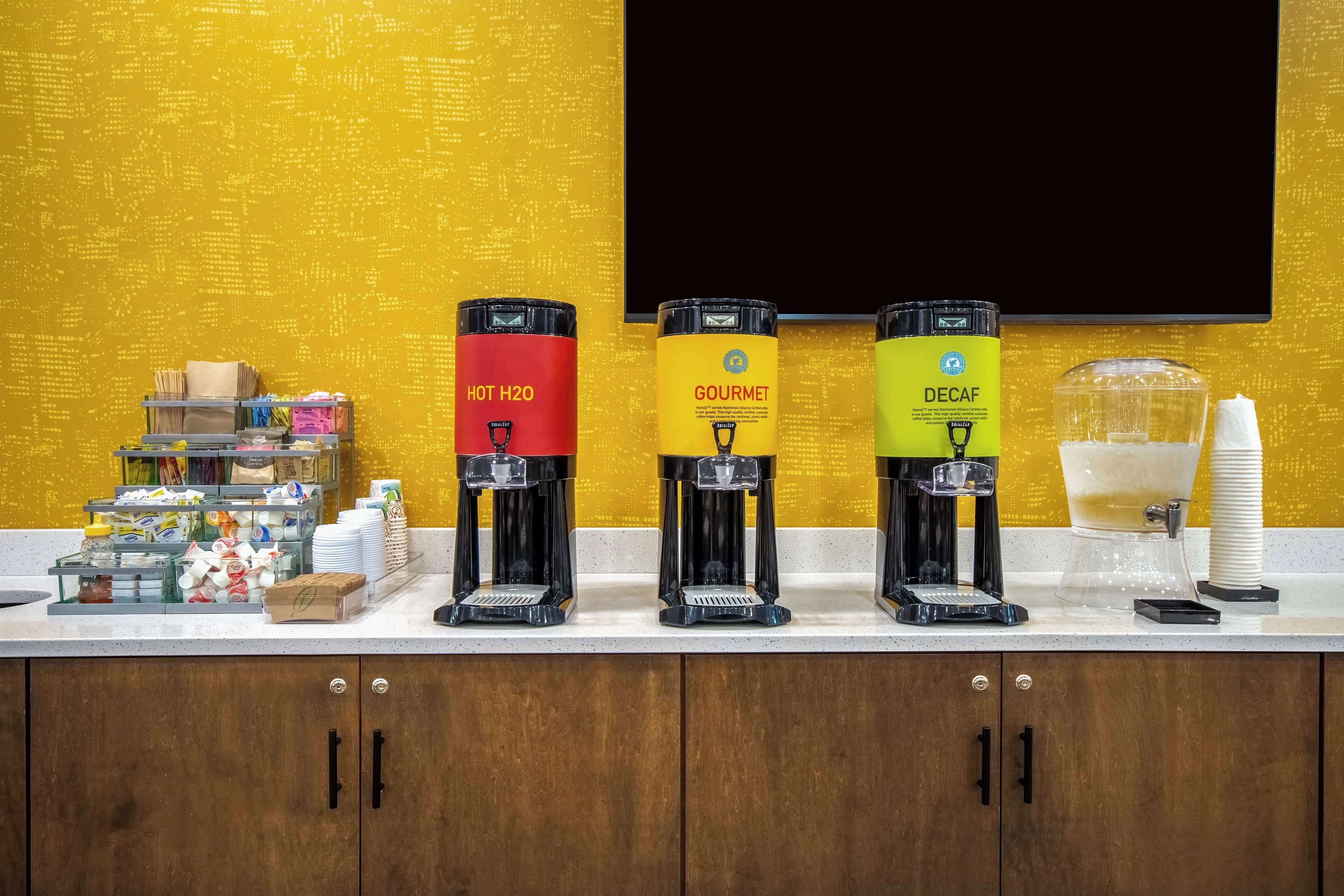 A coffee station with three dispensers labeled 'HOT H2O', 'GOURMET', and 'DECAF'.