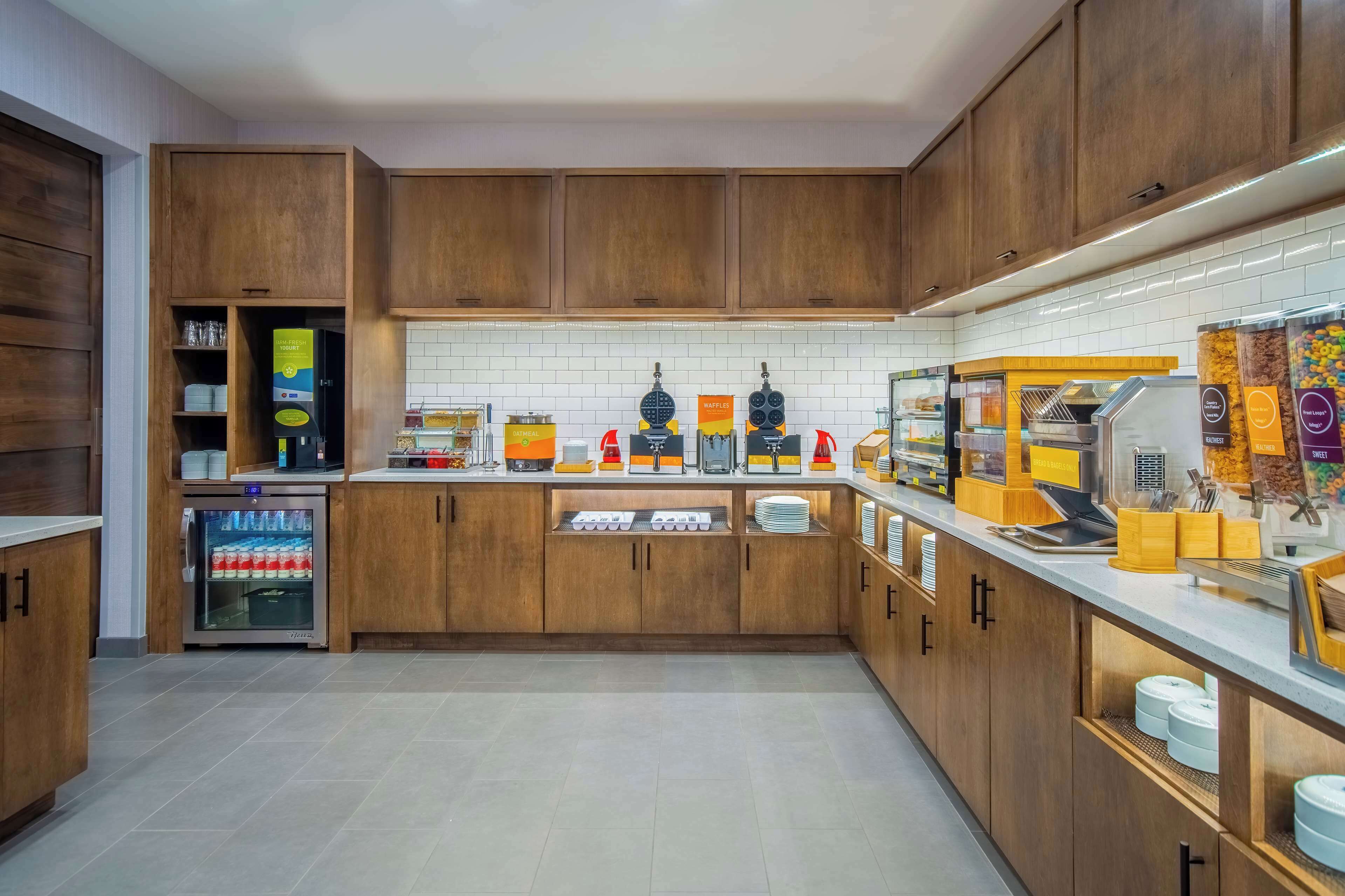 A modern kitchen with wooden cabinets, a built-in coffee station, and a refrigerator.