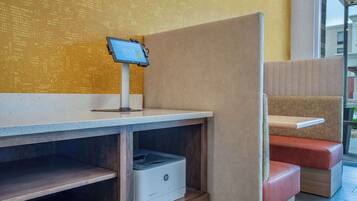 Un área de descanso con un quiosco digital, una impresora y un banco acolchado.