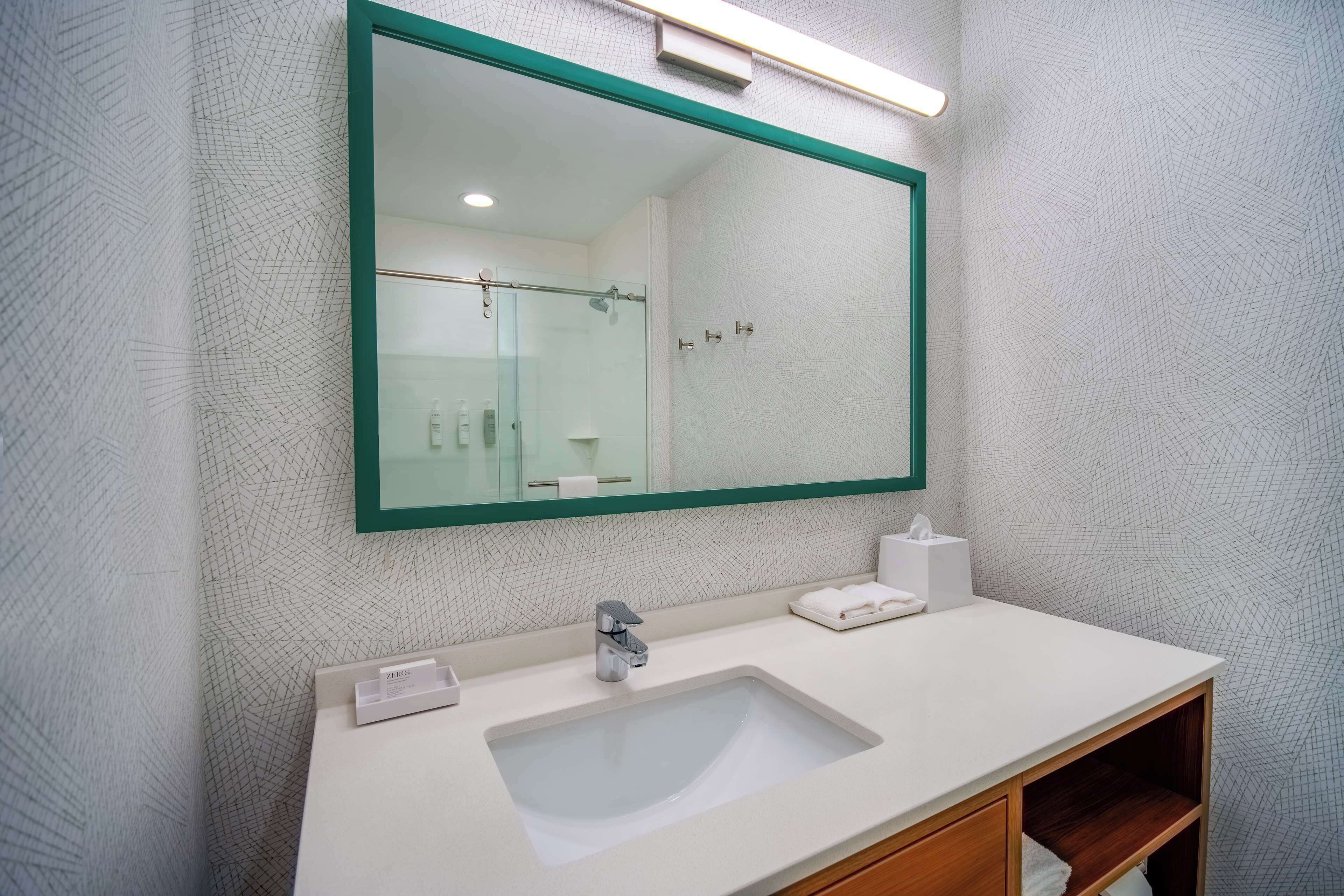A bathroom with a large mirror, white sink, and a towel rack.