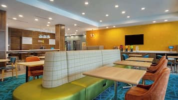 Un moderno vestíbulo de hotel con áreas de estar, un mostrador de recepción y una cocina al fondo.