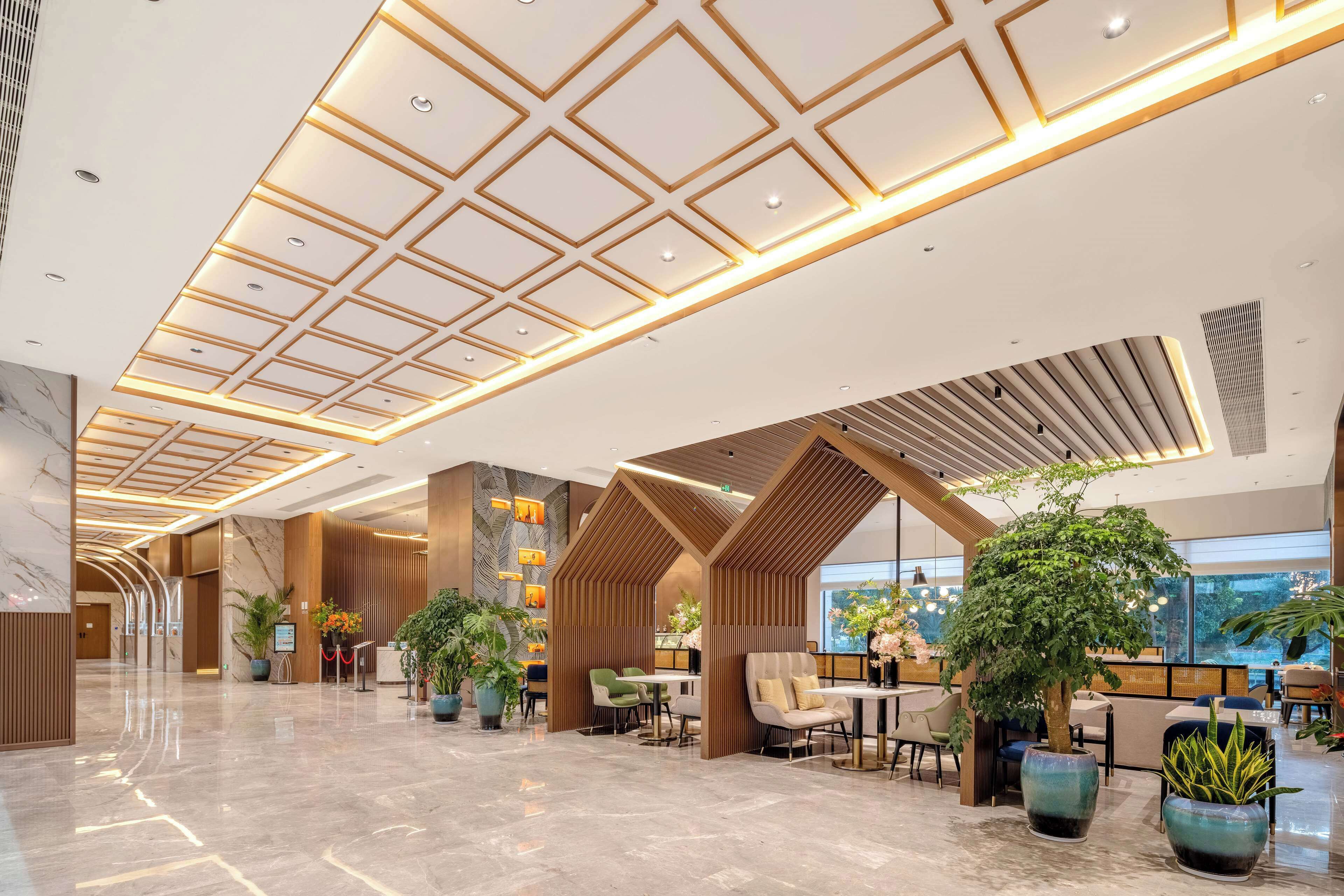 A spacious lobby with a high ceiling, modern lighting, and multiple seating areas.