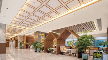 A spacious lobby with a high ceiling, modern lighting, and multiple seating areas.