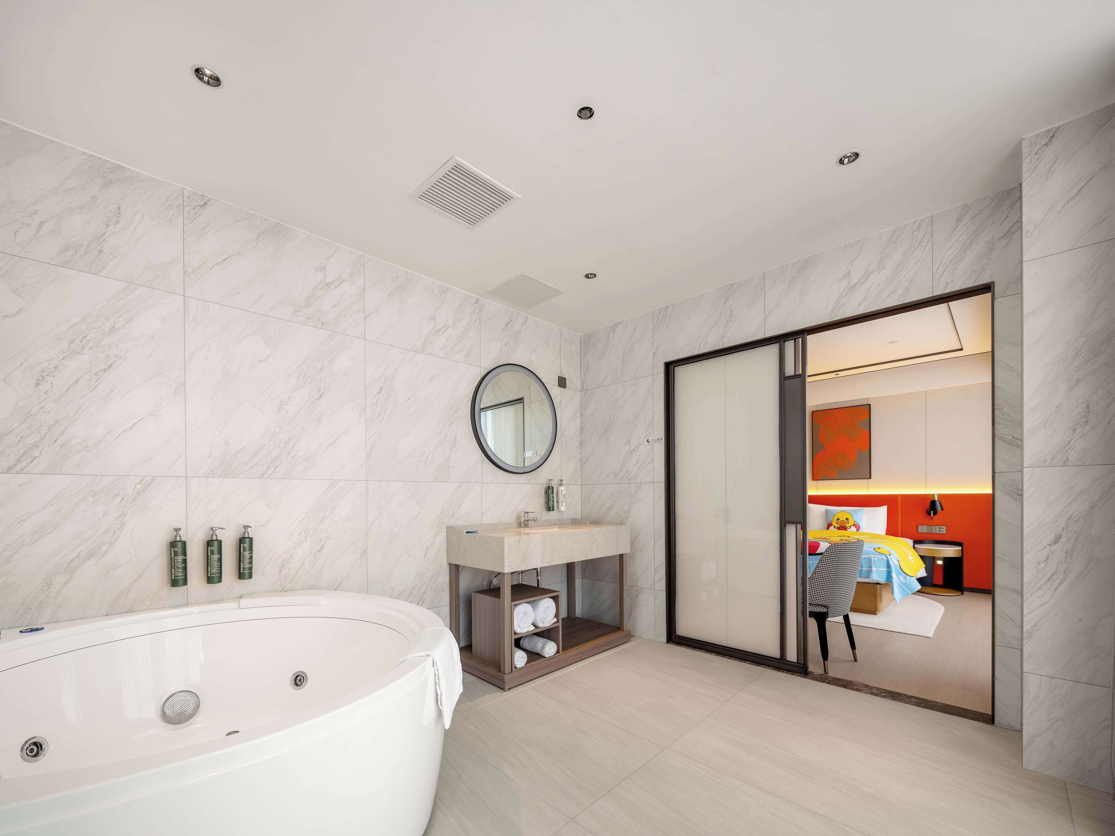 Un baño moderno con una bañera independiente, un espejo redondo y un mueble de tocador con lavamanos.
