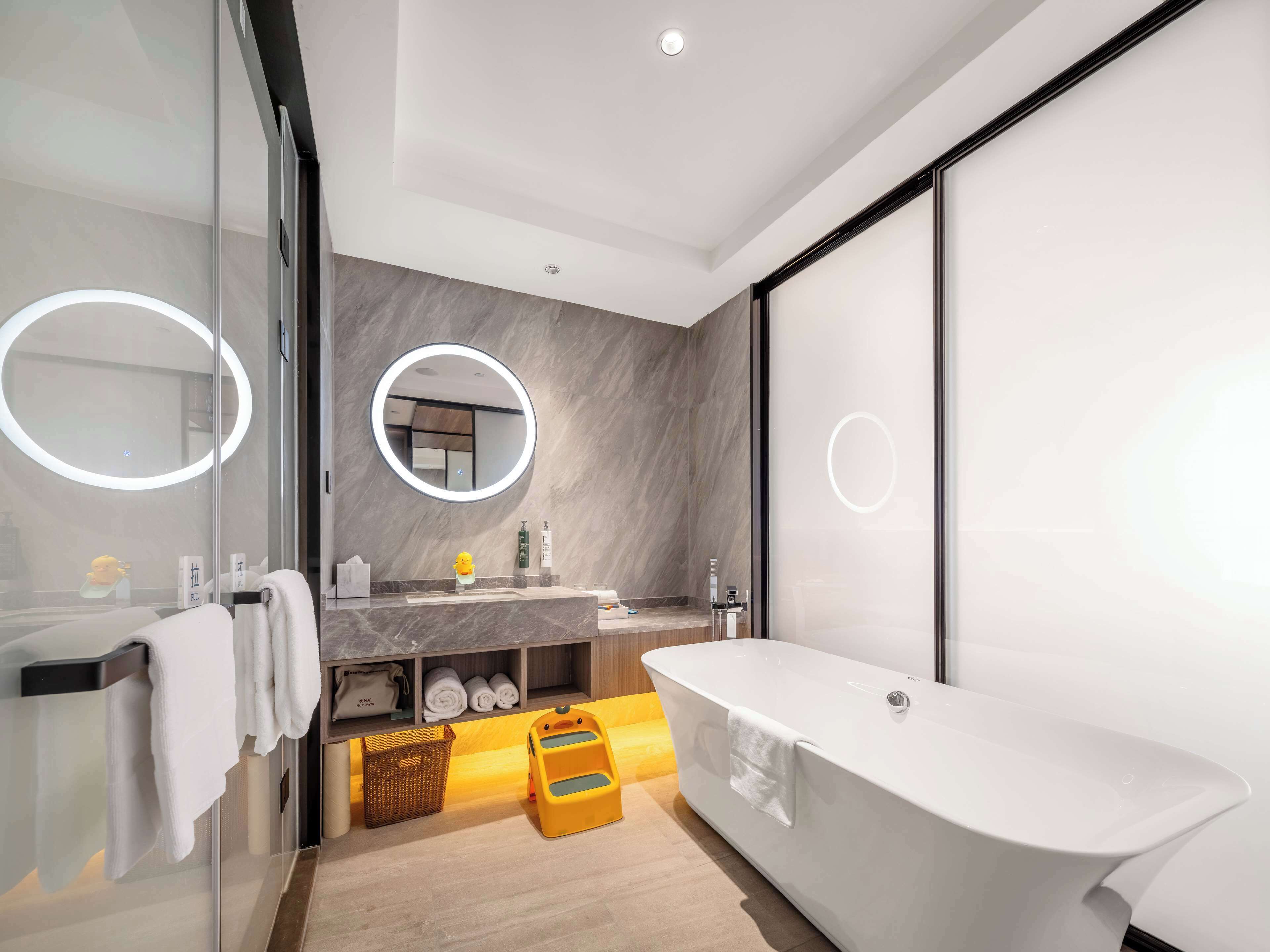 A modern bathroom with a freestanding bathtub, a vanity with a mirror, and a glass shower enclosure.