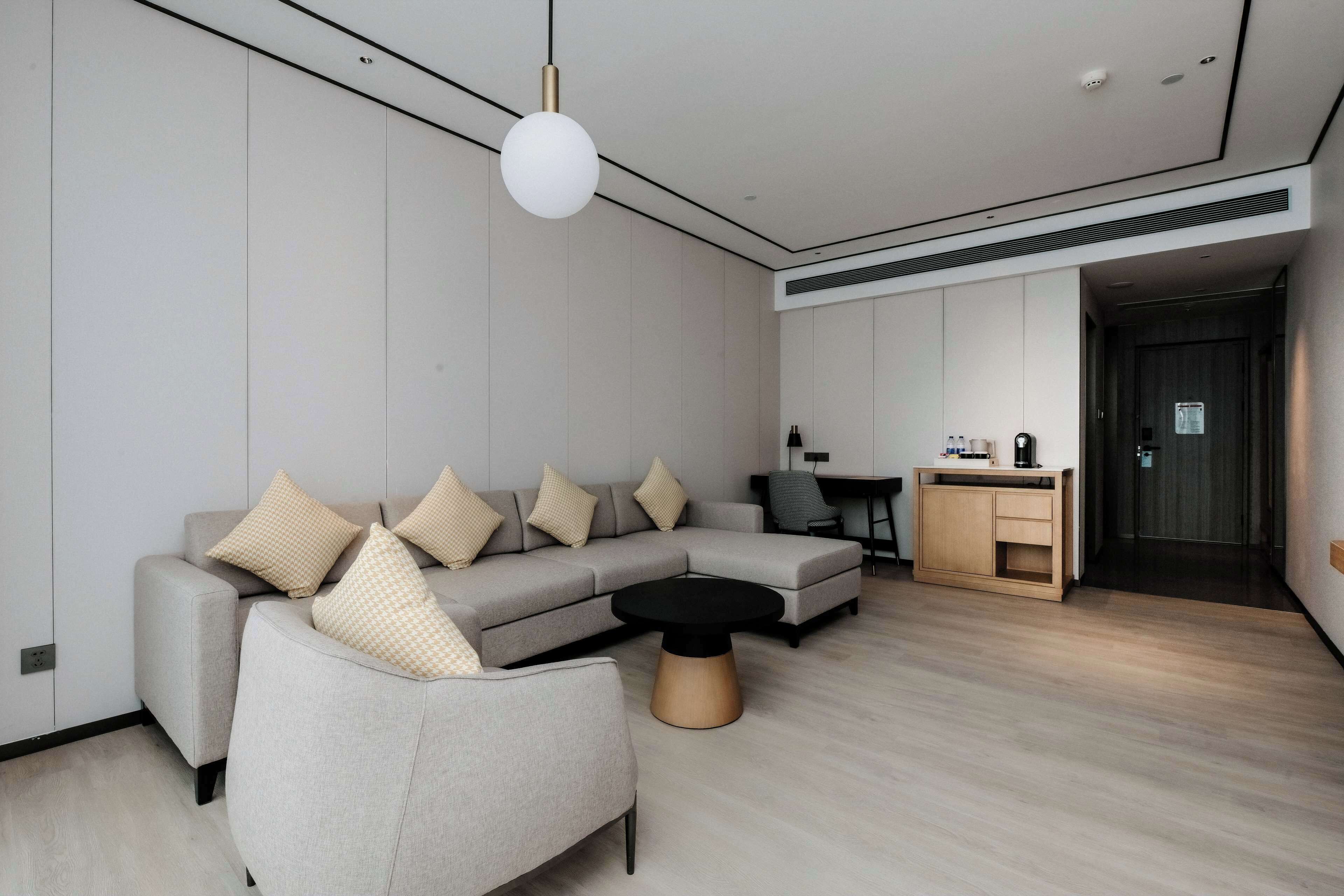 A modern living room with a sectional sofa, a round coffee table, and a dining area with a small cabinet.
